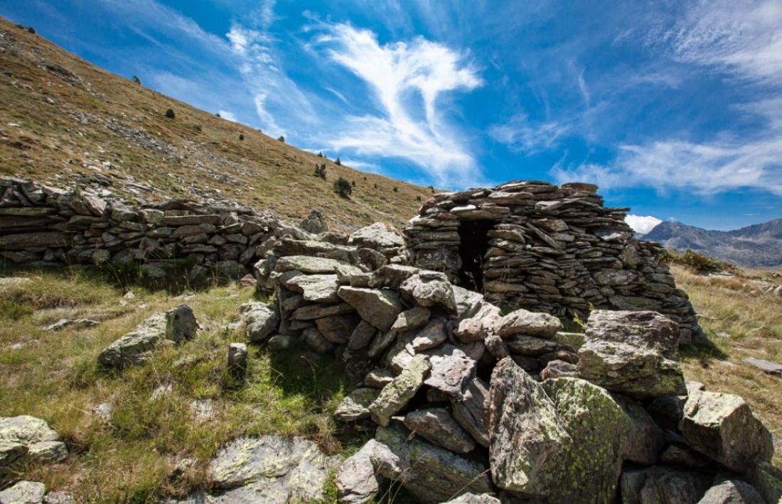 Cabana de l'orri de Rusca, a Canillo, adaptada al terreny i adossada a una roca.