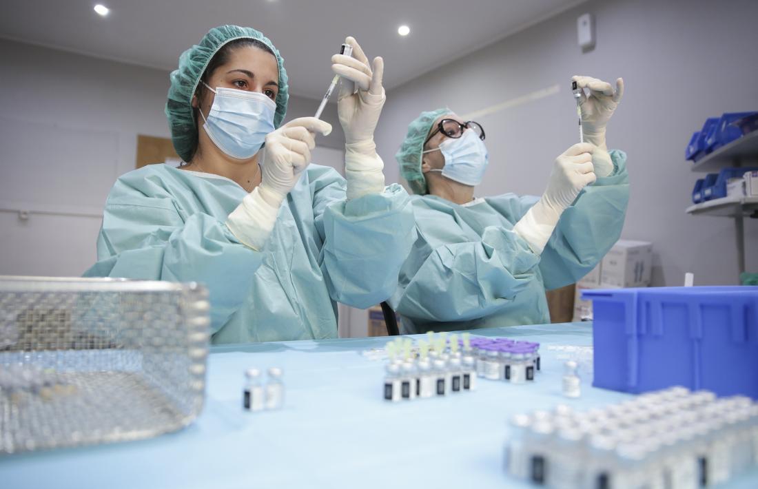 Dues infermeres preparen les dosis del vaccí que s'han d'administrar a la població.