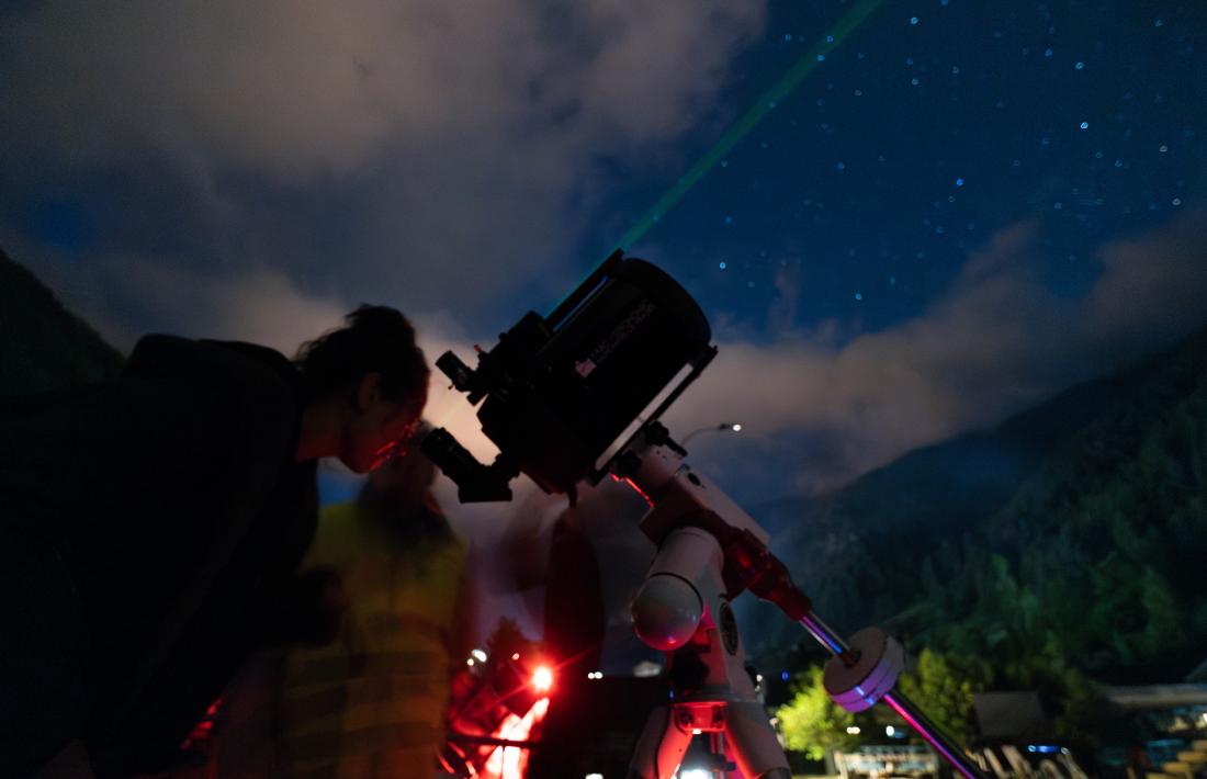 Una persona observant amb un telescopi el cel estrellat d'Arinsal.