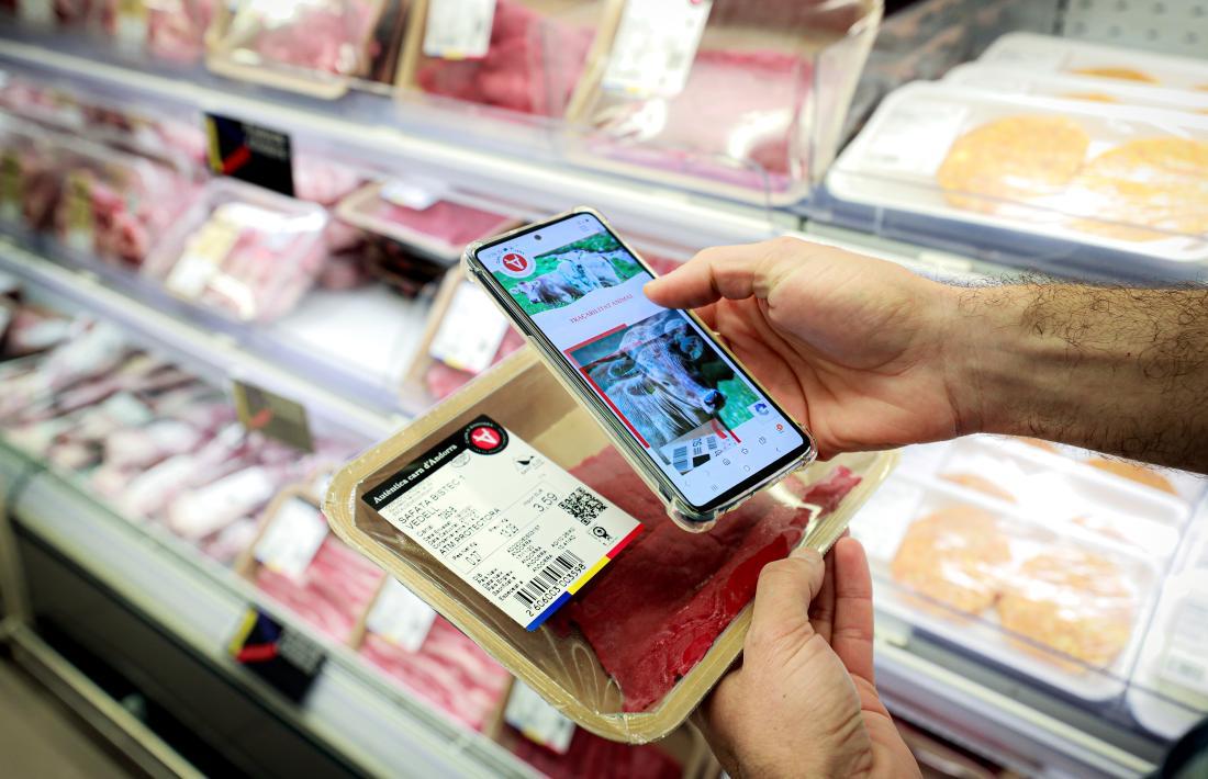 Una persona buscant la informació d'una safata de carn en un supermercat.