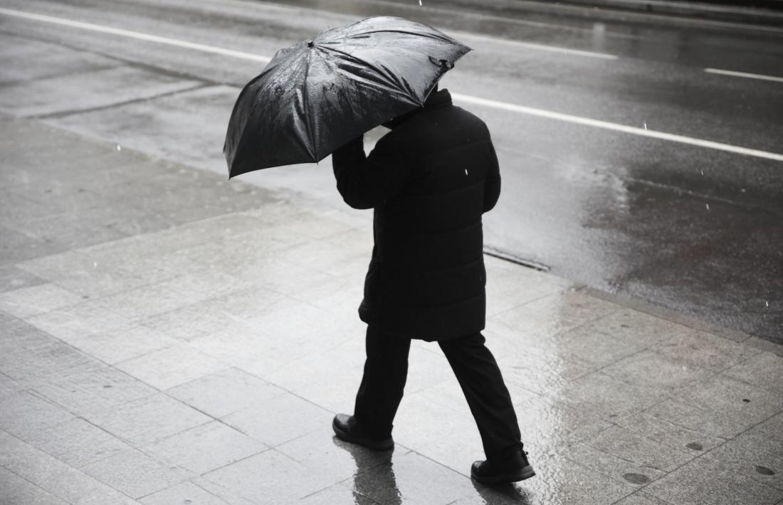 Un home passeja pel carrer un dia de pluja i fred.